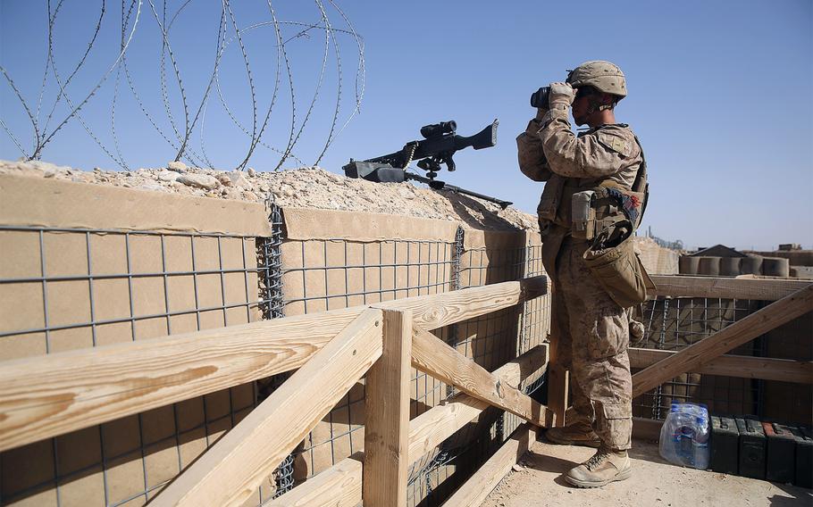 A U.S. Marine scans the surrounding area with binoculars from a security post during a mission in Helmand province, Afghanistan, on June 13, 2014. 