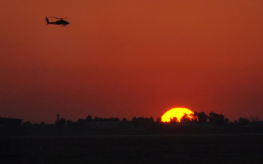 An Apache helicopter flys over Balad Air Base, Iraq at sunset Feb 11, 2007. )