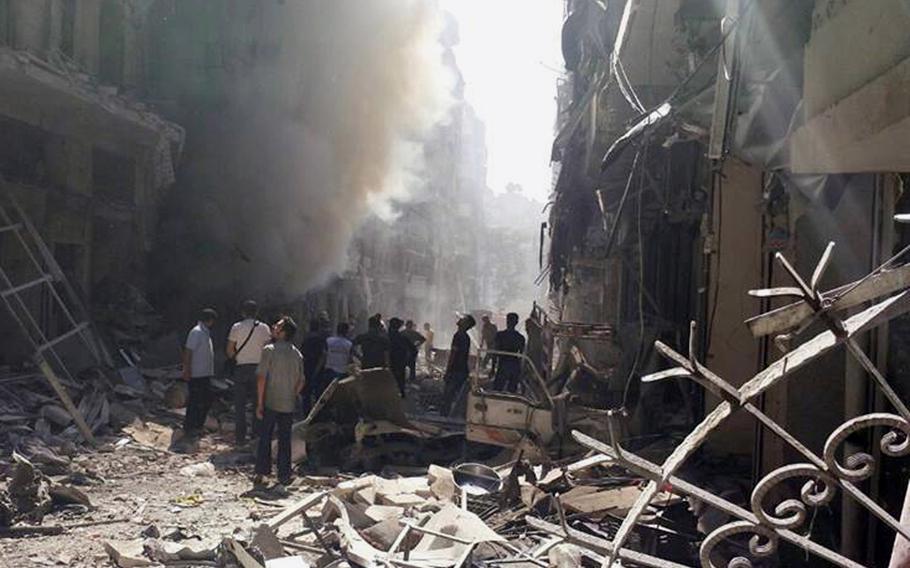 This photo provided by the anti-government activist group Syrian Observatory for Human Rights, which has been authenticated based on its contents and other AP reporting, shows Syrians inspecting a site amid the rubble of destroyed buildings following a Syrian government airstrike at Karm al-Jabal area in Aleppo, Syria, Thursday, June 26, 2014. Syrian warplanes struck the area in the northern province of Aleppo killing and wounding dozens of people, activists said. 
