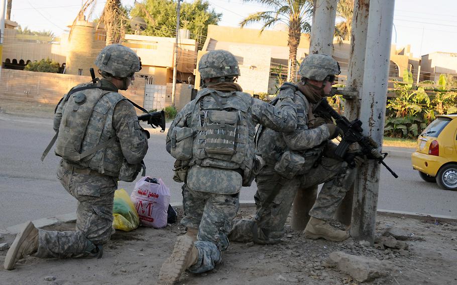 U.S. troops take a knee at a street corner before continuing a patrol in Baghdad in this file photo from Oct. 23, 2011.