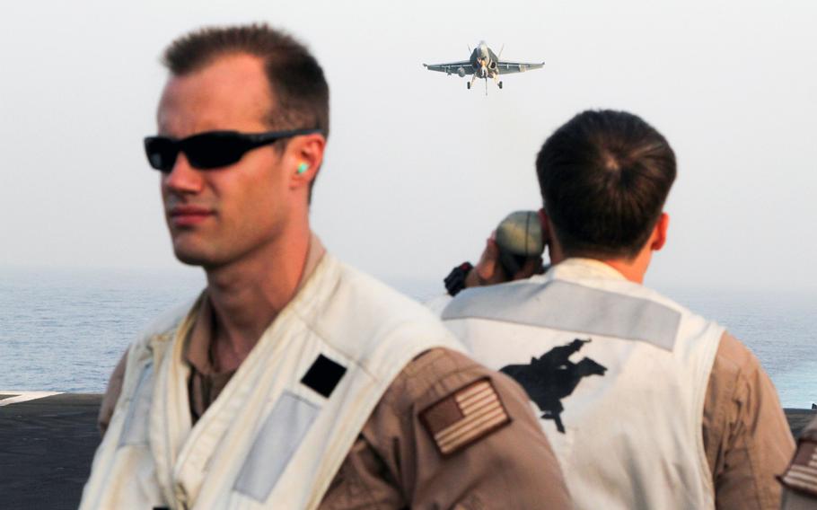 A landing signal officer aboard the USS George H.W. Bush, underway in the Persian Gulf,  talks to the pilot of an F/A 18 Hornet on approach for recovery, Aug 10, 2014. F/A 18s are among launched from the Bush are among aircraft  conducting air strikes in Iraq.
