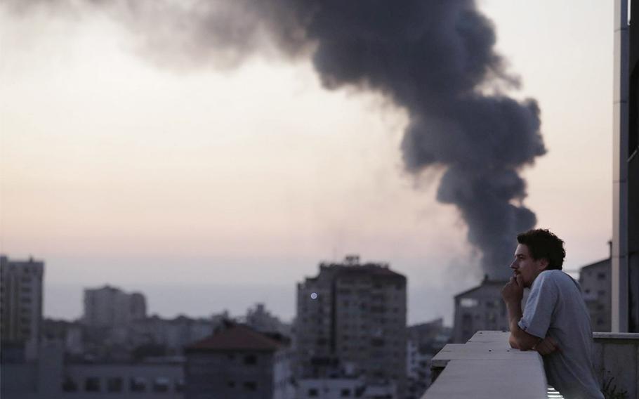 This photo taken in August, 2014 shows Associated Press video journalist Simone Camilli on a balcony overlooking smoke from Israeli Strikes in Gaza City. Camilli, 35, was killed in an ordnance explosion in the Gaza Strip, on Wednesday, Aug. 13, 2014 together with Palestinian translator Ali Shehda Abu Afash and three members of the Gaza police. Police said four other people were seriously injured, including AP photographer Hatem Moussa.