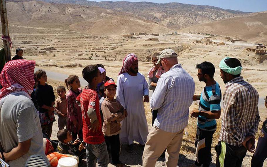 A member of the U.S. assessment team on Sinjar Mountain is greeted by locals near Sinjar, Iraq, on Aug. 13, 2014. The team helped determine the impact of current U.S. humanitarian assistance efforts and whether additional supplies or assistance were required.