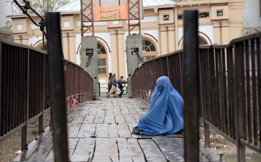 An Afghan woman sits in the rain in Kabul on Nov. 3, 2014. The city saw no major acts of violence as thousands of Afghans gathered to commemorate the day of Ashoura.