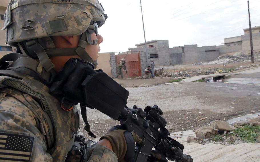 A U.S. soldier peeks out from behind a wall during a gunfight in Mosul, Iraq, in 2009.