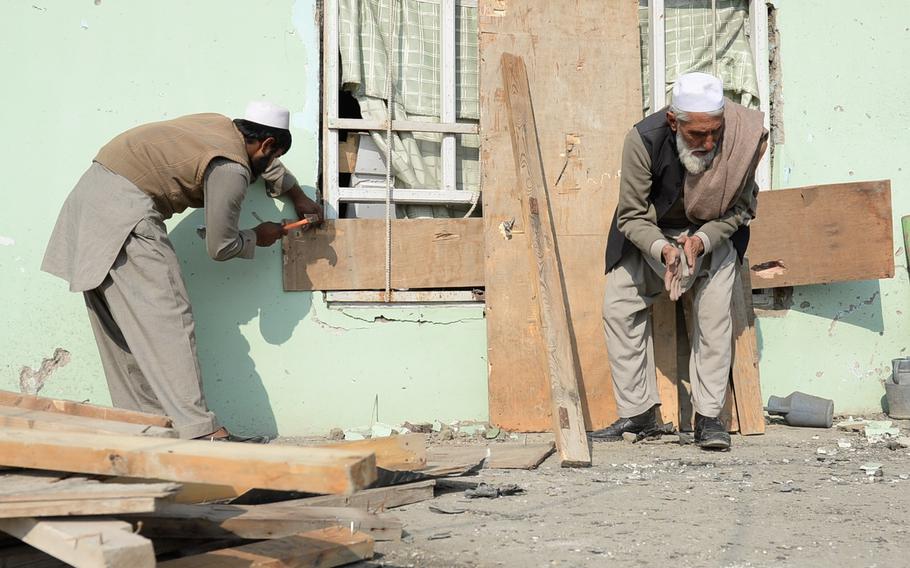 Civilians clean up pieces of metal and broken glass at a mosque in the Qalai Wazir neighborhood in eastern Kabul, after a massive Taliban car bomb struck a British Embassy convoy moving through the area on Thursday, Nov. 27, 2014.