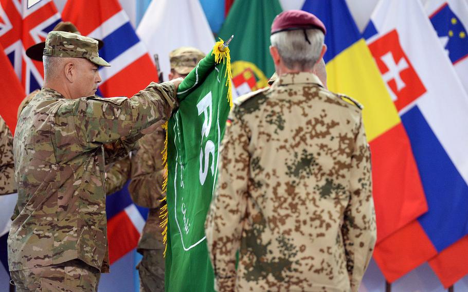Gen. John Campbell, commander of the U.S.-led military coalition in Afghanistan, unfurls the flag of Resolute Support, the name of the new military mission in the country that will focus on training and advising Afghan forces. The ceremony on Sunday, Dec. 28, 2014 in Kabul marked the end of the International Security Assistance Force.