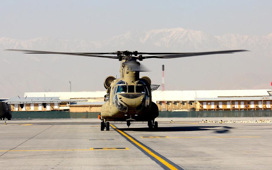 A CH-47 Chinook helicopter sits on the tarmac at Kabul International Airport on Dec. 8, 2014. Three contractors working with the international military coalition in Afghanistan were shot and killed Thursday, Jan. 29, 2015, on the military side of the airport. 