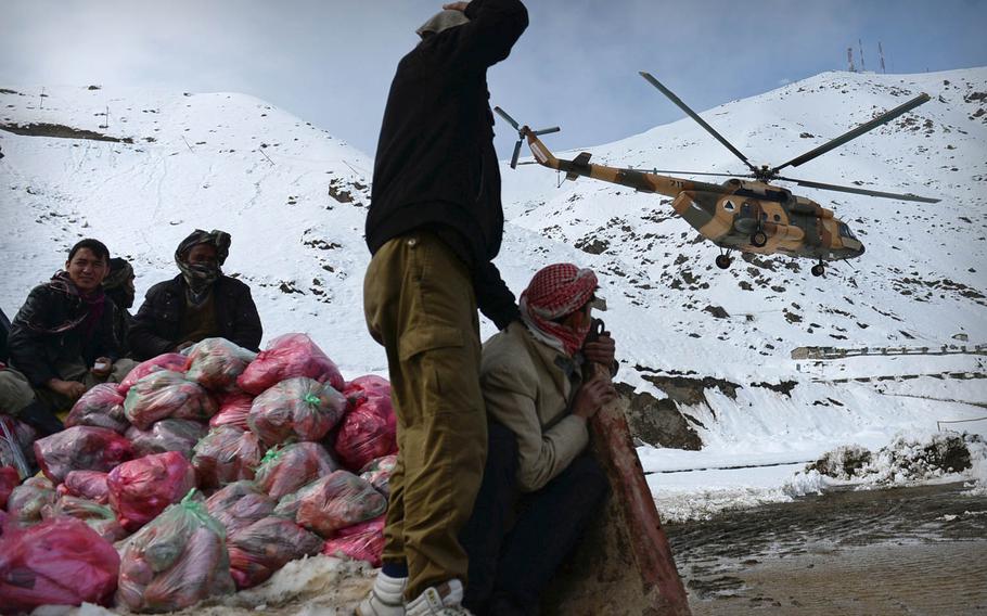 Men sitting in a truck full of emergency meals watch an Afghan Air Force Mi-17 helicopter take off from a field in Panjshir valley in central Afghanistan on Saturday, Feb. 28, 2015. Several days of heavy snow and avalanches left about 200 people dead across the country and thousands more stranded in remote villages.

