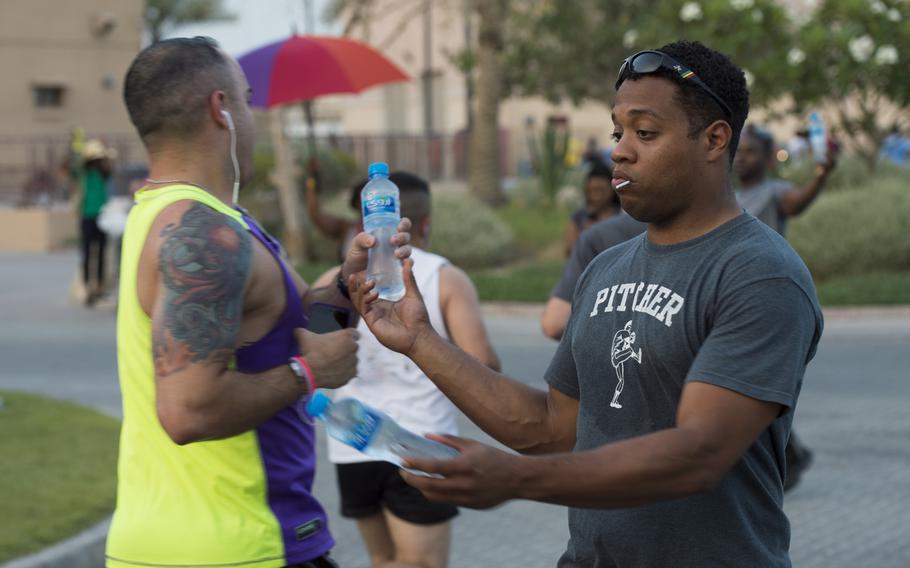 Volunteers hand out water to passing runners during Naval Support Activity Bahrain's Pride Month  race June 17, 2015.



