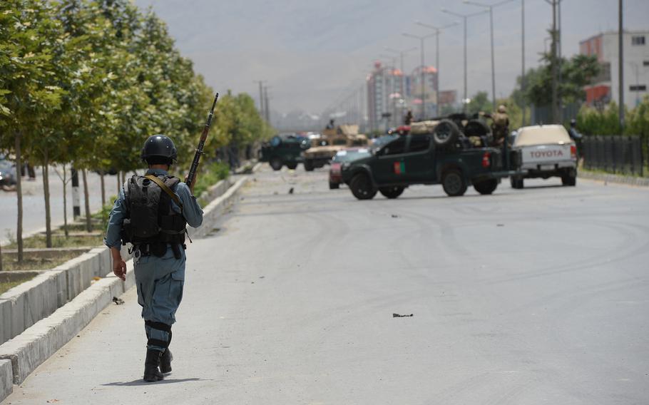 An Afghan police officer walks toward the site of a Taliban attack on the Parliament building in Kabul on Monday, June 22, 2015. 