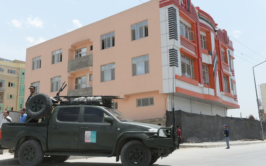 An Afghan police vehicle sets up a security cordon in front of a building damaged during a complex attack by Taliban insurgents on the Afghan Parliament building in Kabul on Monday, June 22, 2015.