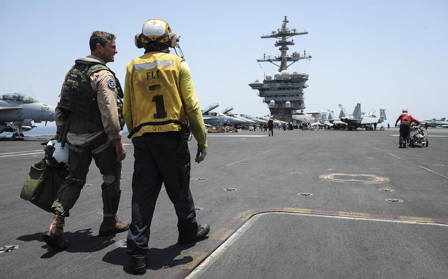 Rear Adm. Andrew Lewis, commander of Carrier Strike Group 12, talks to a sailor after his last flight aboard the aircraft carrier USS Theodore Roosevelt, which is deployed in the Persian Gulf, on July 17, 2015. 