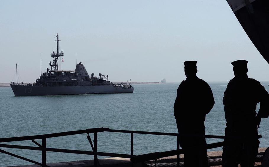 Two Iraqi navy sailors watch as the mine countermeasures ship USS Dextrous approaches the Iraqi navy pier in Umm Qasr, Iraq in this Sept. 2009 photo.
