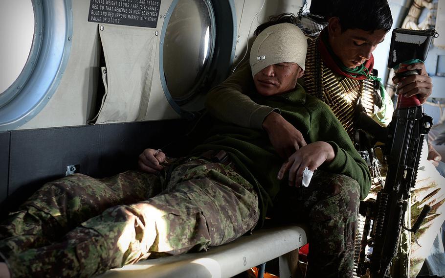 Inside an Afghan air force Mi-17 helicopter, a soldier comforts a comrade injured by an improvised bomb in Uruzgan province on Jan. 6, 2015. Afghan security forces have taken the brunt of casualties in the unfinished war as international troops have withdrawn.
