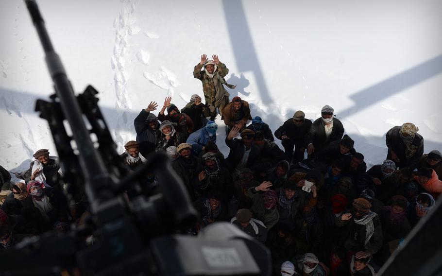 Villagers gesture to a departing Afghan air force Mi-17 after it dropped supplies to their community on Saturday, Feb. 28, 2015. Dozens of such villages were cut off after deadly avalanches buried roads and houses.
