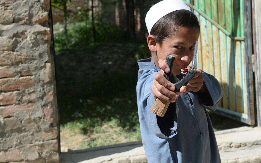 An Afghan child shows off his slingshot near Bagram Air Field on May 9, 2015. The soldiers who patrol his village expect rocks to hit their vehicles, but say it's just a game the kids play. 

