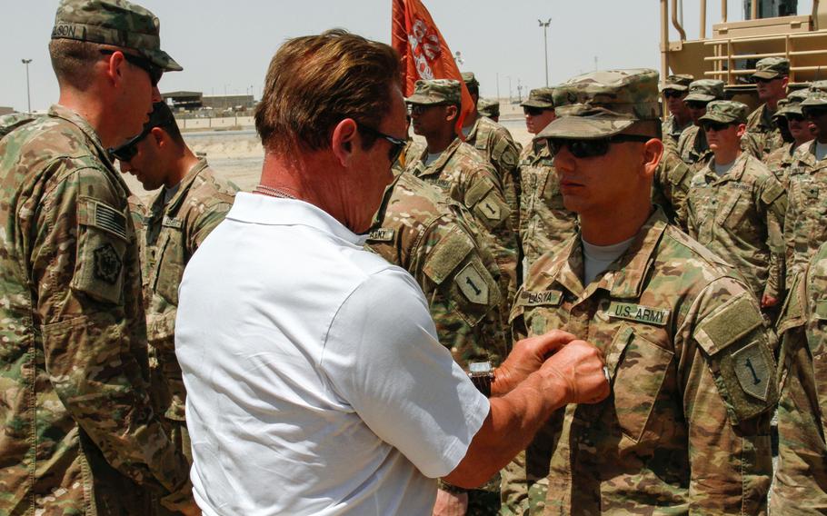 Arnold Schwarzenegger, the former governor of California, places specialist rank on Spc. Ray Lasoya, 82nd Engineer Battalion, during a promotion ceremony at Camp Arifjan, Kuwait, Wednesday, April 27, 2016. Schwarzenegger was in Kuwait to film a National Geographic documentary, "Years of Living Dangerously," focused on climate change.

