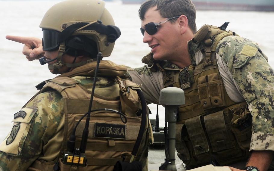 In an August, 2015 file photo, Lt. David Nartker, right, assigned to Coastal Riverine Squadron (CRS) 3, talks with an Indonesian "Kopaska" Naval Special Forces member while practicing small boat tactics and maneuvers during Cooperation Afloat Readiness and Training (CARAT) Indonesia 2015.