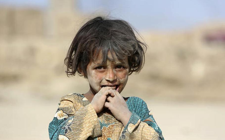 In this Monday, Oct. 3, 2016, file photo, an Afghan girl poses for photograph on the outskirts of Kabul, Afghanistan. The U.N. mission in Afghanistan says the number of children killed or wounded in the country's conflict has increased in the first nine months of 2016. 