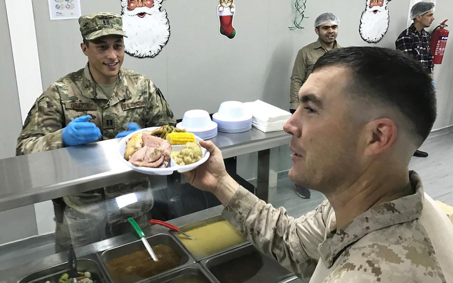 Air Force Capt. Robert Orallo, of San Antonio, Tex, serves a Christmas meal to Marine Capt. Matthew Alvis of Hallsville, Tex., at a dining facility on the Combined Joint Operations Center at the international airport in Irbil, Iraq, on Sunday, Dec. 25, 2016.
