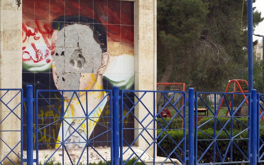 In a 2013 file photo, a defaced portrait of Syrian president Bashar Assad is seen on a wall in Raqqa, Syria.