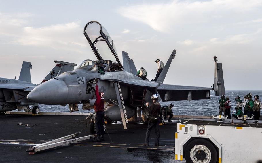 Flight deck crew onboard the aircraft carrier USS George H.W. Bush conduct a pre-flight check in the morning on an F/A-18 Hornet in the Persian Gulf.
