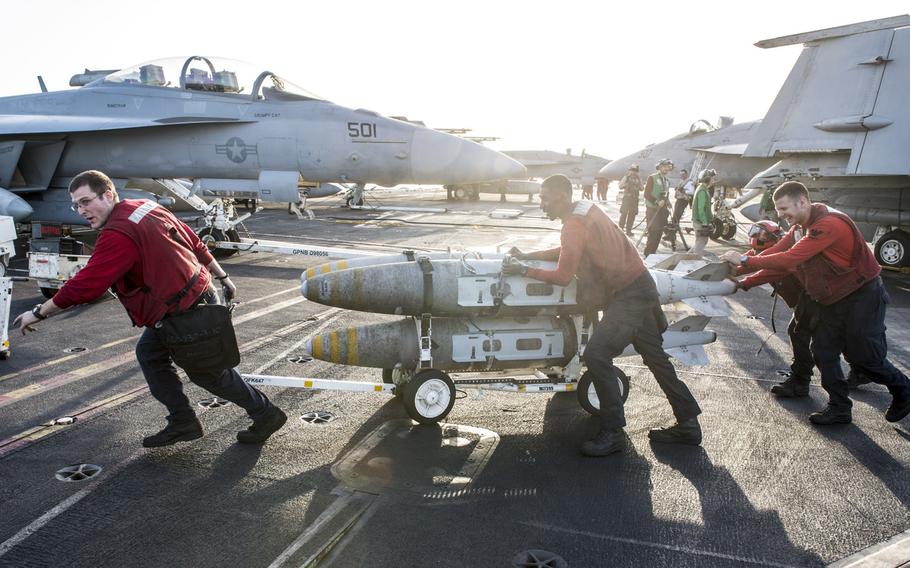 Aviation ordnance teams push munitions weighing thousands of pounds to aircraft during a morning load out onboard the aircraft carrier USS George H.W. Bush in the Persian Gulf on April 20, 2017.
