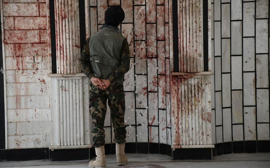 An Afghan security official looks at blood on the walls of the Imam Zaman mosque in Kabul, Afghanistan, on Saturday, Oct. 21, 2017, a day after an Islamic State suicide bomber launched a deadly attack on the mosque.