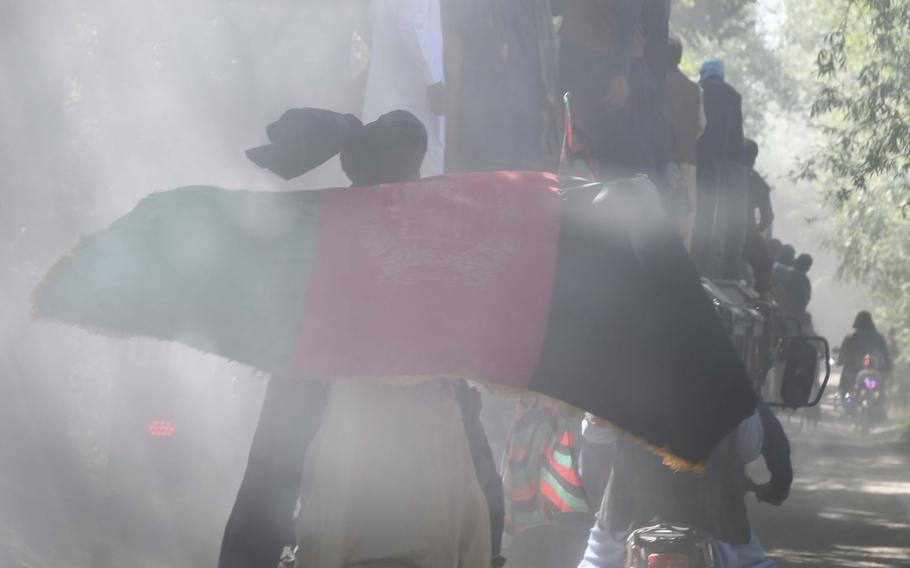 A man flying an Afghan flag passes soldiers of the Afghan National Army's 203rd Corps as they venture to a Taliban stronghold in Logar province, a mission only made possible by unprecedented mutual cease-fires between the Taliban and the Afghan government over the weekend.
