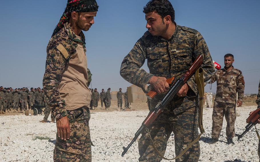 In a July 31, 2017 file photo, an instructor with the Syrian Democratic Forces, watches a Syrian Arab trainee clear his rifle during small arms training in Northern Syria. Last weekend's airstrikes against the Islamic State were monitored and guided by SDF fighters on the ground in Syria.