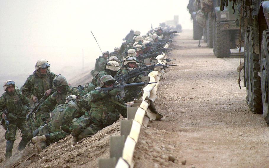 U.S. Marines line up behind a road barrier as they secure a key bridge along a main supply route during the march to Baghdad, Iraq in March 2003. 