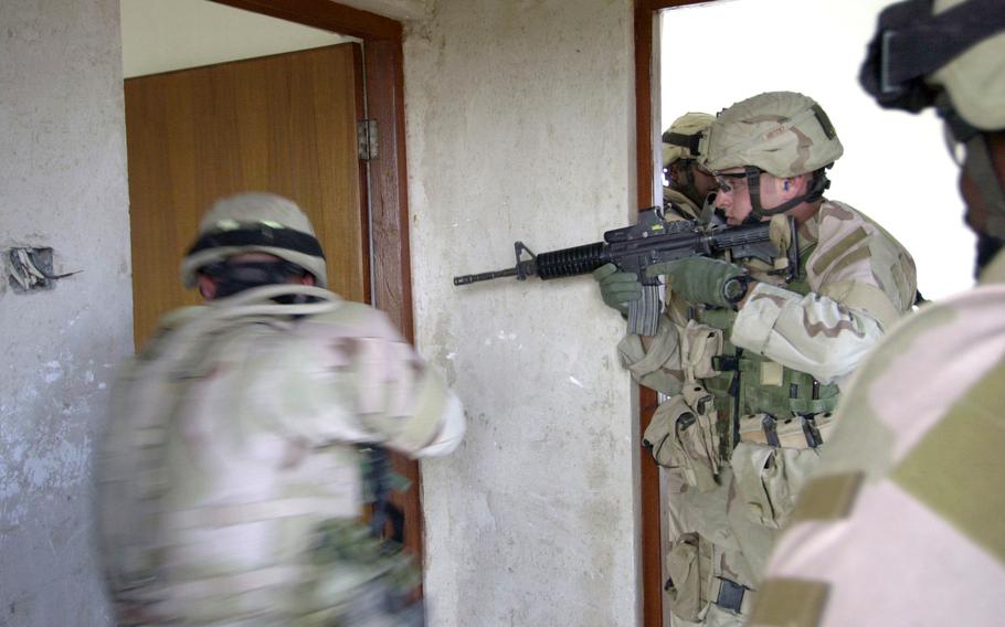 Soldiers from Company A, 1st Battalion, 69th Infantry Regiment, conduct a room-to-room search during a patrol of farmhouses near Taji, Iraq, in December 2004.