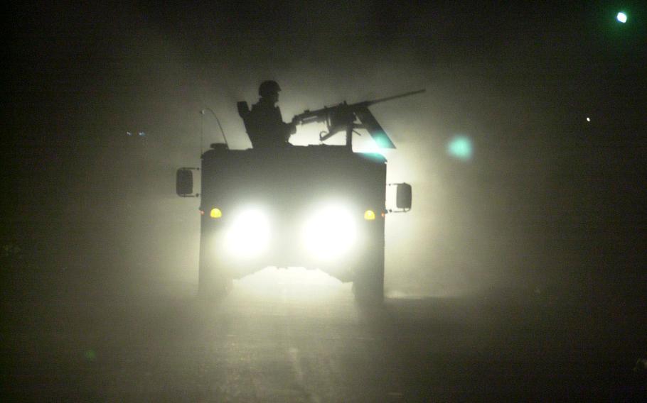 A Humvee gunner is outlined by the headlights of trailing vehicles as a convoy rolls through Baghdad at 3 a.m., on its way to a raid south of the city in October 2003. Soldiers often work around the clock in what they call the Three-Block War. 