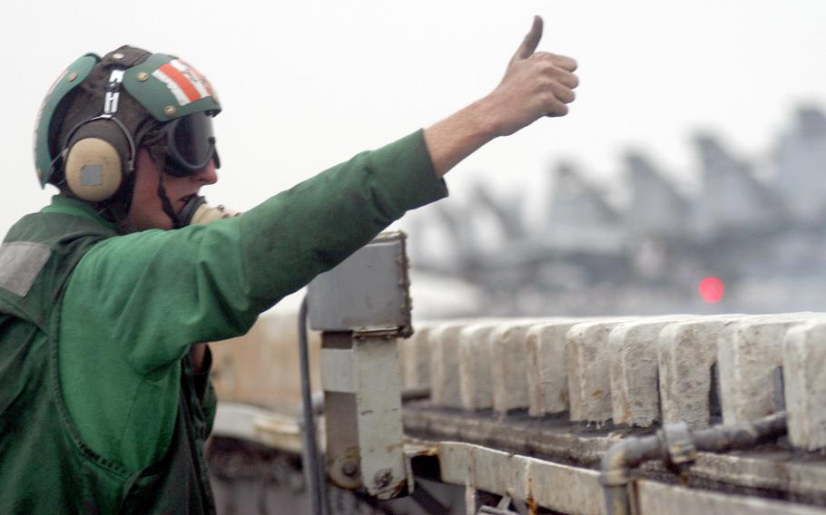 Petty Officer 2nd Class Eric Klostermann, an aviation boatswain's equipment mate, gives the thumbs-up for an aircraft to launch off the USS Kitty Hawk in March 2003.