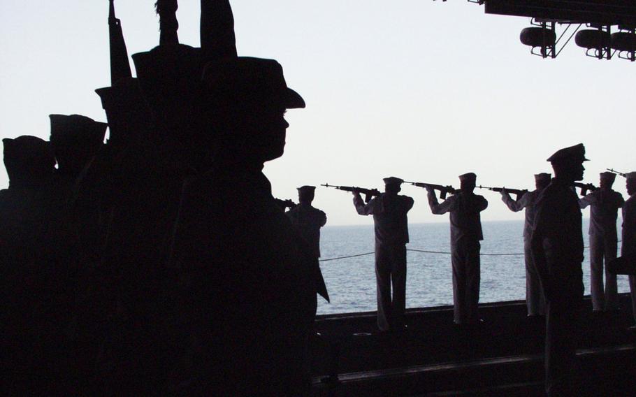 Members of an honor guard, left, stand as sailors fire a 21-gun salute during an April 2003 memorial service aboard the USS Kitty Hawk for Lt. Nathan “O.J.” White, a Carrier Air Wing 5 member killed in combat.