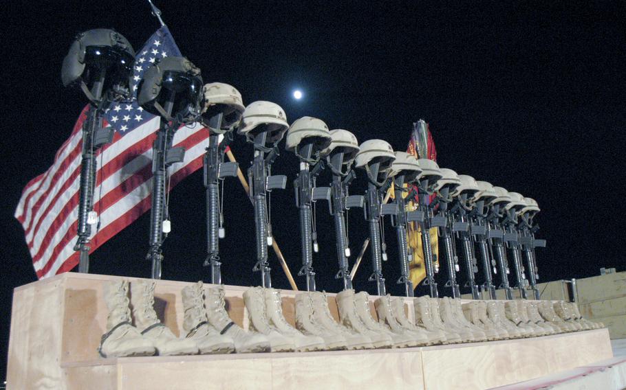 Fifteen sets of helmets, rifles, dog tags and boots are placed in front of a U.S. and Army flag as a memorial to 15 soldiers killed when a Chinook helicopter was shot down Nov. 2, 2003. Hundreds of soldiers and civilians attended the memorial service at al-Asad airbase in Iraq. A 16th soldier died later from his injuries. 