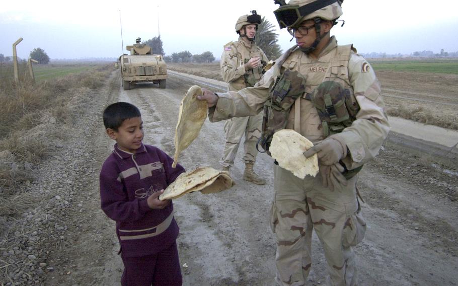 An Iraqi boy in Hora al Bosh gives freshly baked flatbread to Spc. Acisclo Melendez of Company A, 1st Battalion, 69th Infantry Regiment, in April 2003. 