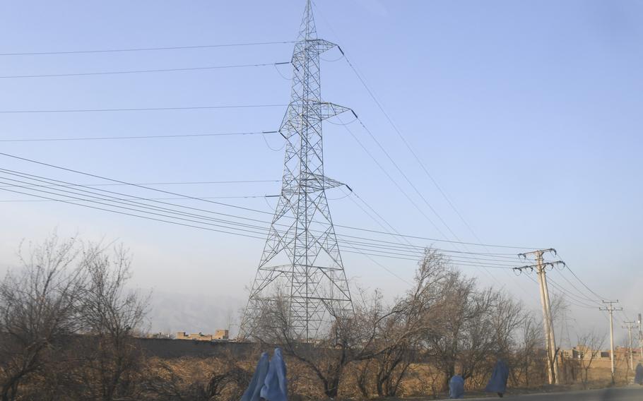 Afghan women are pictured here on Sunday, Dec. 24, 2017, donning the head-to-toe burqa as they walk along a highway in Parwan province, where power lines have been built under U.S.-funded contracts aimed at bringing economic development for rural areas and cheaper electricity to support outlying military posts.

