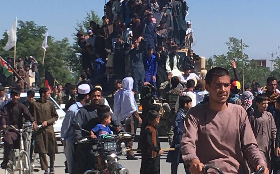Men crowd atop an Afghan army MRAP (mine-resistant ambush protected vehicle), waving the Afghan and Taliban flags on Saturday, June 16, 2018, in Logar province's capital of Pul-e-Alam, the second day of jubilant gatherings there as Afghan military officials, civilians and Taliban militants gathered to celebrate cease-fires announced unilaterally by the Kabul government and the Taliban. 