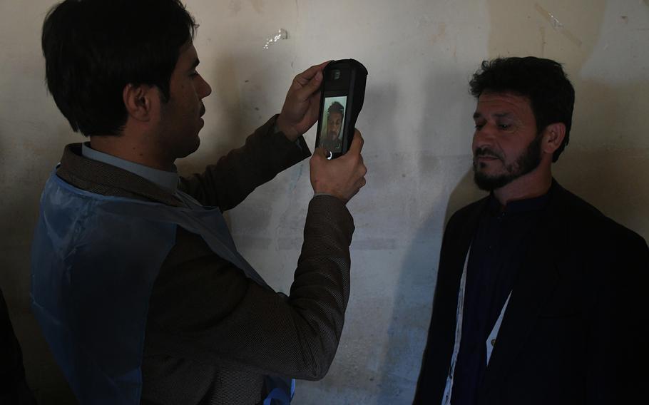 An election worker identifies a voter at a polling center in Kabul on Saturday, Oct. 20, 2018.