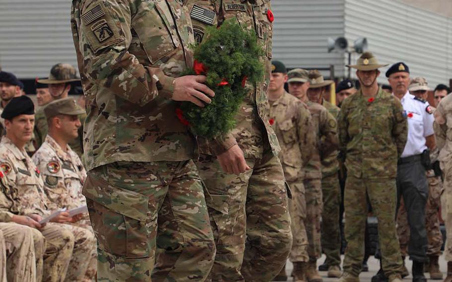 U.S. Army Lt. Gen. Paul LaCamera, left, commander of the 18th Airborne Corps and Combined Joint Task Force - Operation Inherent Resolve (CJTF-OIR), and Command Sgt. Maj. Charles Albertson walk towards the center of the ceremony with a wreath to be placed on a centerpiece at the Armistice Ceremony at Union III, Baghdad on Nov. 11, 2018.  
