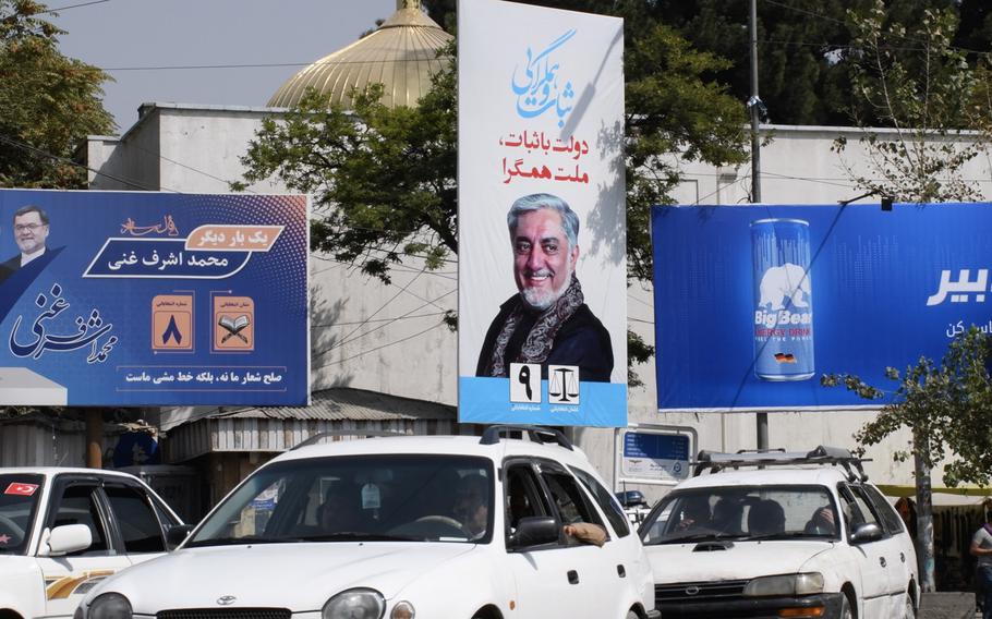 Cars in Kabul drive past campaign billboards in Kabul for the two frontrunners in Afghanistan's presidential election, which is to be held on Saturday, Sept. 28, 2019.