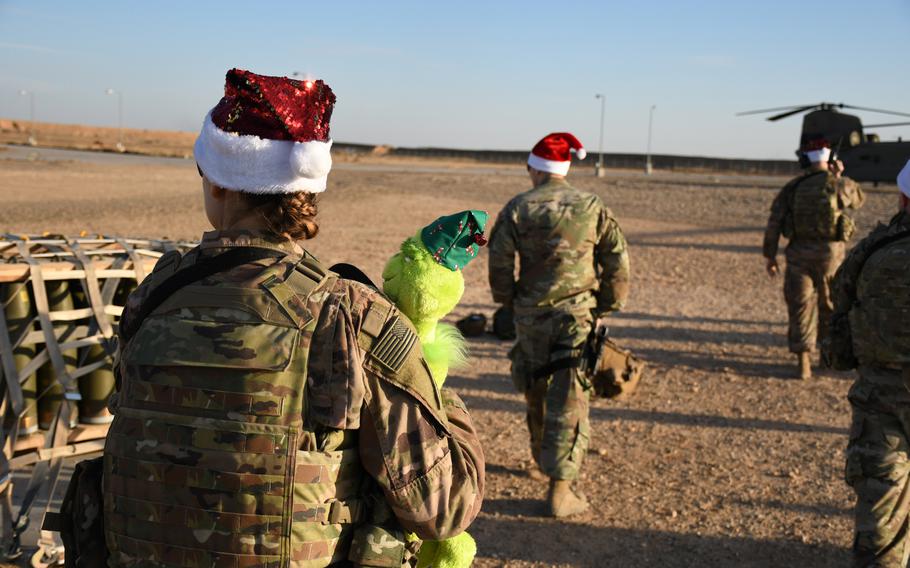 Sgt. Brittany Rockwell carries a stuffed Grinch toy back to a CH-46 Chinook during a special holiday mission to spread cheer to troops deployed to austere camps in Syria's Deir el-Zour province on Monday, Dec. 23, 2019.

