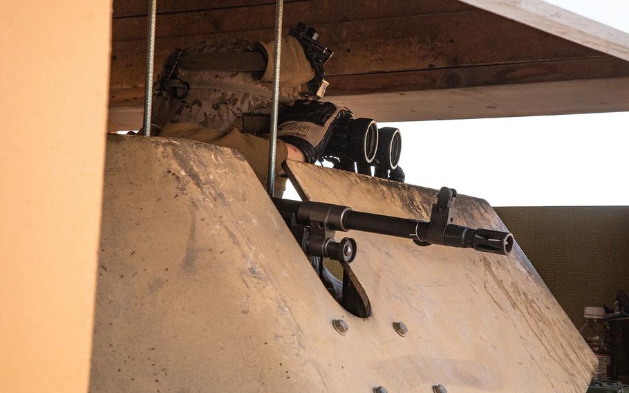 A U.S. Marine assigned to the Special Purpose Marine Air-Ground Task Force-Crisis Response-Central Command 19.2, looks through binoculars at an M240-B medium machine gun post in response to protests at the Baghdad Embassy Compound in Iraq, Jan. 1, 2020. 