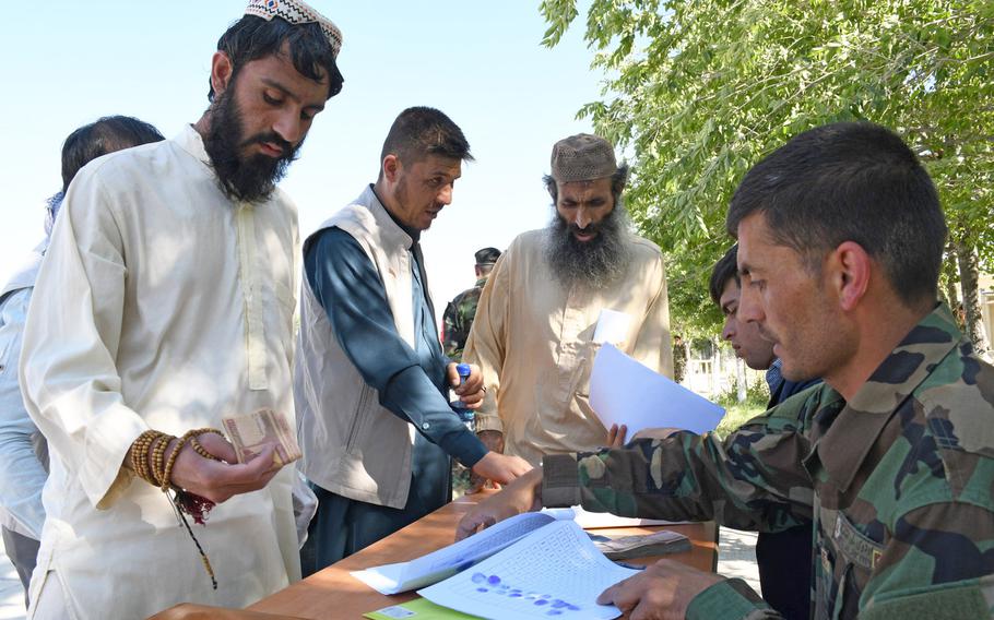 A Taliban prisoner at Bagram prison on Tuesday, May 26, 2020, receives the equivalent of about $65 after having is thumb print taken and signing a pledge not to return to the battlefield. About 900 prisoners were released across the country Tuesday. 