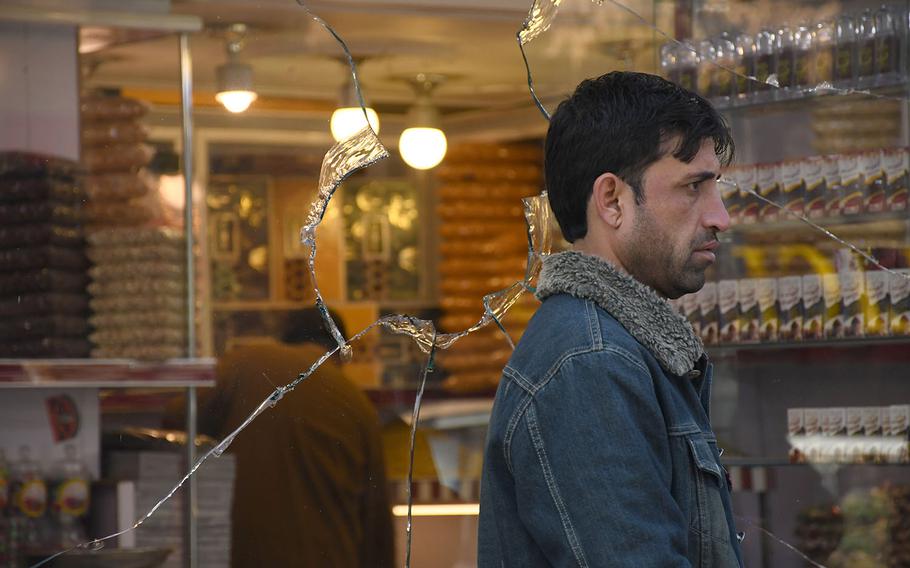 A man walks past a shop window in Kabul shattered by rocket blasts on Saturday, Nov. 21, 2020.