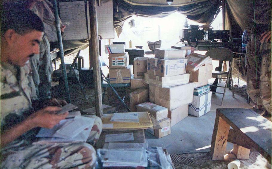A soldier opens care mail while deployed to the Middle East as part of Operations Desert Shield and Desert Storm. 

