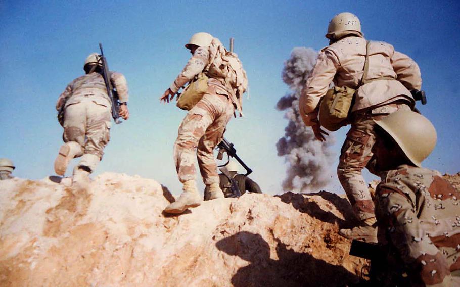 Smoke billows in the distance as soldiers rush forward in a photo taken by Army Sgt. Kirby Lee Vaughn while deployed during the Gulf War, which lasted from Aug. 2, 1990, to Feb. 28, 1991. 

