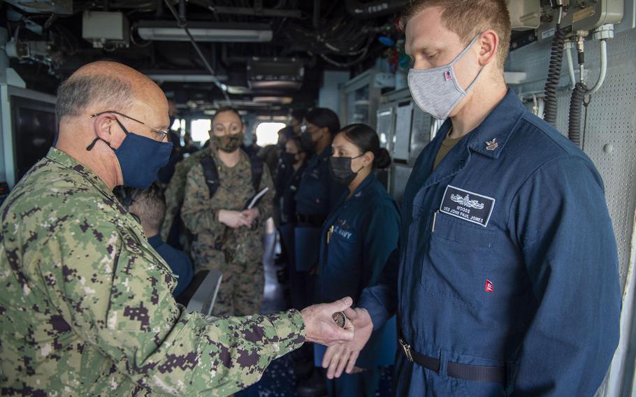 Adm. Mike Gilday, chief of naval operations, presents a challenge coin to operations specialist Petty Officer 1st Class Anthony Woods in the pilot house aboard the destroyer USS John Paul Jones, in the Persian Gulf, Jan. 13, 2021.  

